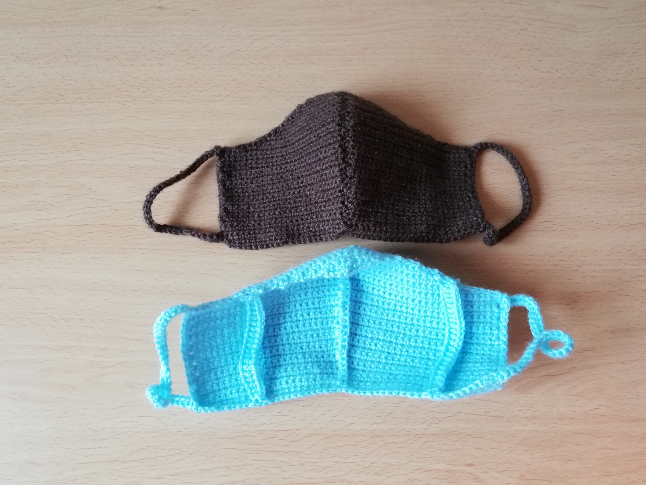 Women- sized brown crochet face mask showing front of the mask and a women-sized turquoise crochet mask showing the back of the mask where the filter insert slot is seen