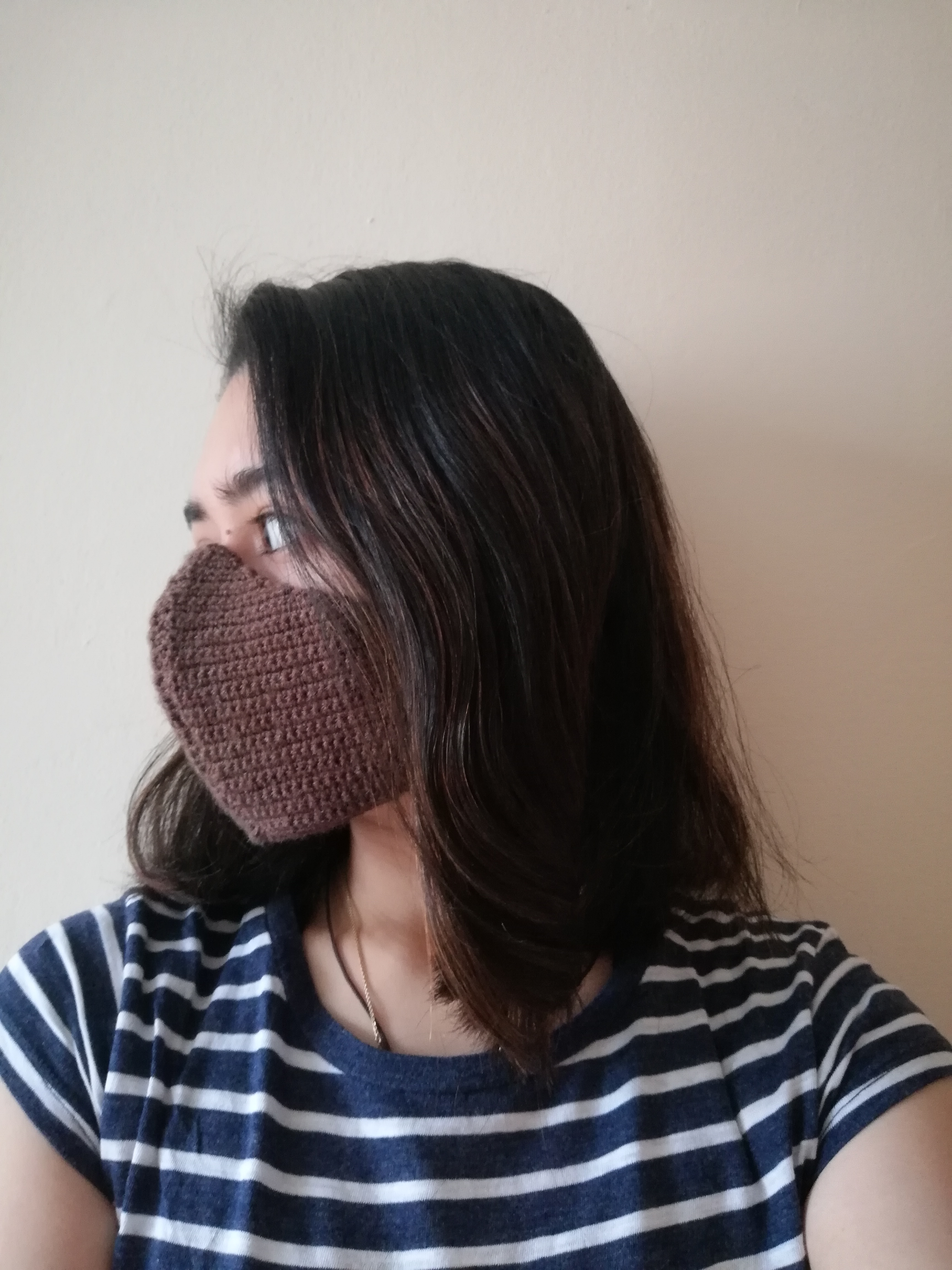 Facing to the right wearing a brown women-sized crochet face mask with hair down