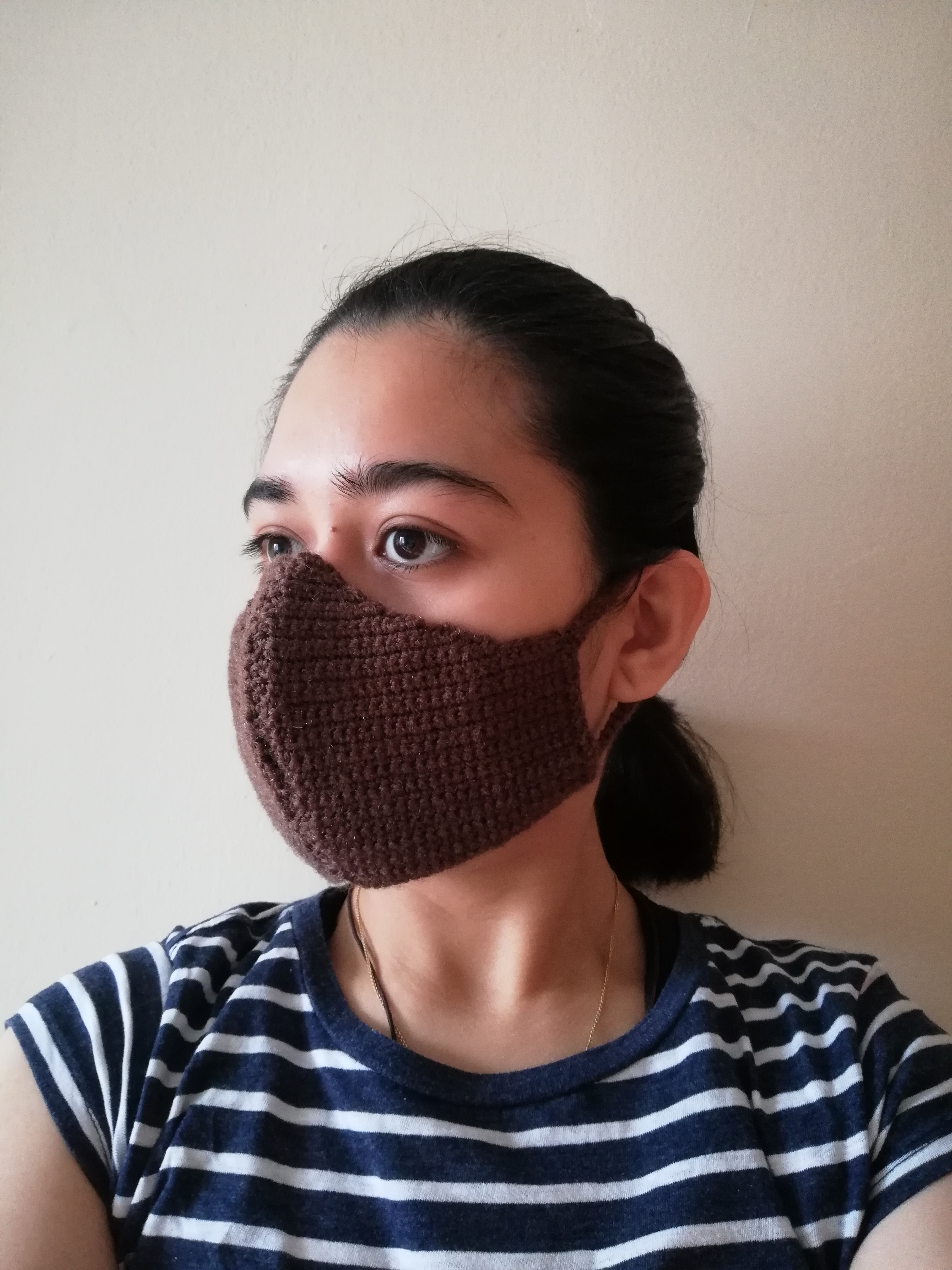 Facing to the right wearing a brown women-sized crochet face mask with hair up
