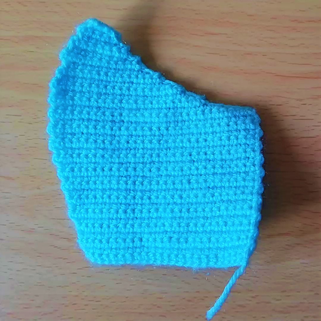 One half of the crochet face mask done in turquoise yarn
